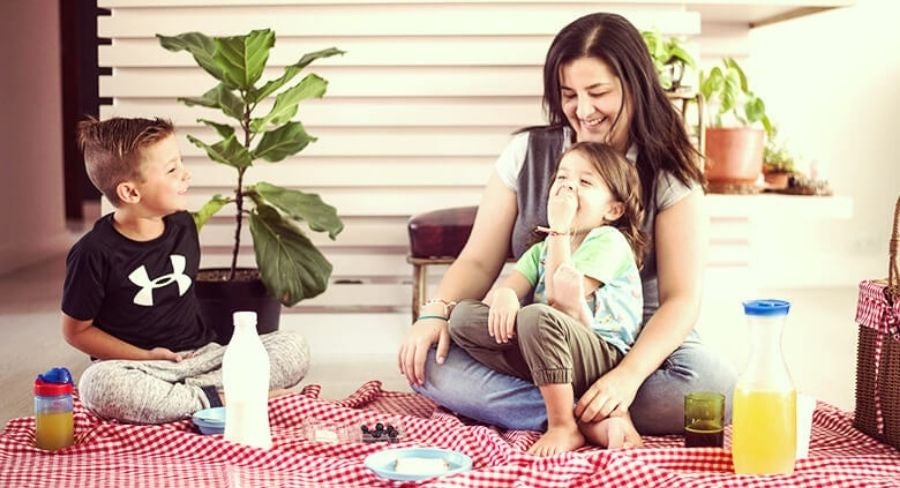 Mamá e hijos comiendo un picnic en casa