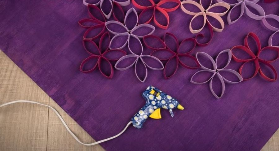 Pegando en una tabla varias flores formadas con tubos de papel higiénico