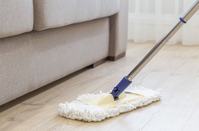 Mopa de microfibra limpiando un piso laminado de madera para la sección de pisos.