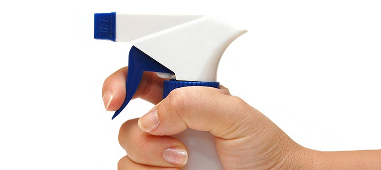 Aplicación uniforme del limpiador con un frasco rociador sobre vidrios y cristales