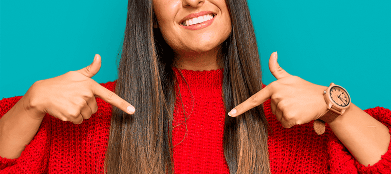 Mujer vistiendo un saco rojo, al que ha aplicado cuidados para la ropa especiales para prolongar su vida útil y mantener la intensidad de sus colores. 