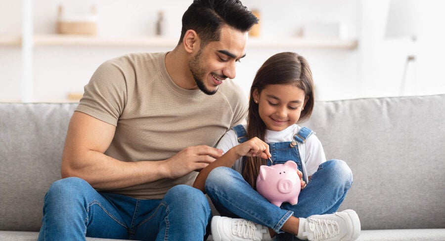 padre e hija metiendo dinero en alcancía